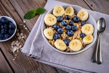 Healthy breakfast,  muesli in bowl with berry and banana on rustic wooden table