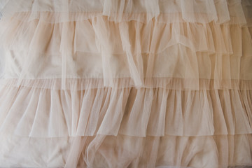 Fabric with lace ruffles. Tulle beige luxury dress with ruffles. Closeup detailed background.....