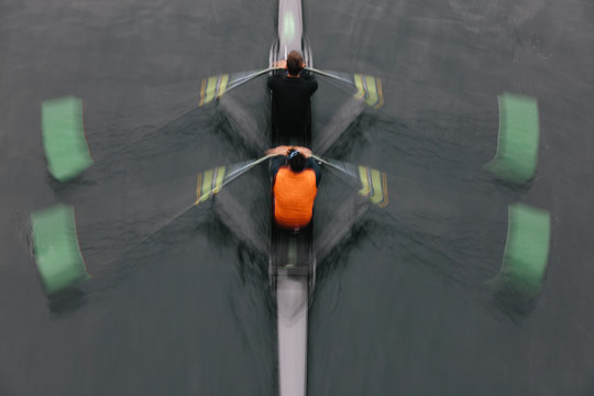 Blurred motion overhead view of a double scull pairs boat, two oarsman in a sculling boat on the water, mid stroke.,Lake Union
