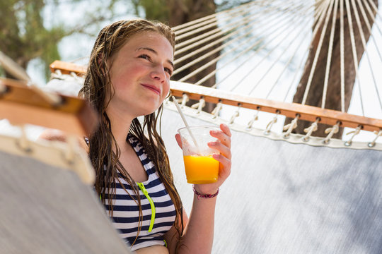 13 Year Old Girl Resting In Hammock Drinking Fruit Drink