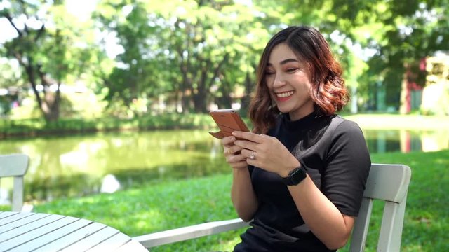 slow-motion of woman using smartphone in park