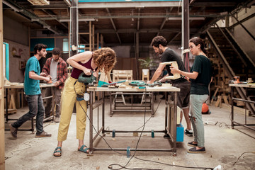 Full length of carpenters working at workbenches in workshop