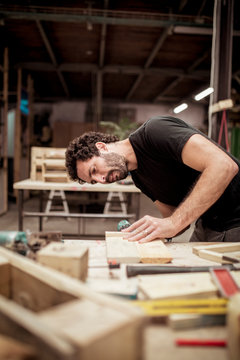 Male carpenter looking at wood while working at workbench