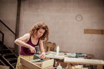 Carpenter drilling while making wooden table at workshop