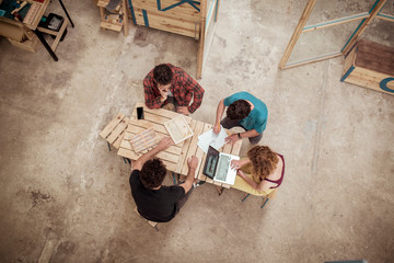 High angle view of carpenters planning while using laptop at desk in workshop