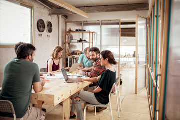 Smiling carpenters planning while working at desk in office