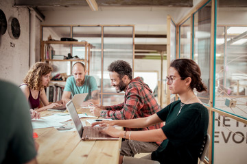 Carpenters working using technologies at desk while sitting in workshop office