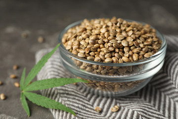 Organic hemp seeds and leaf on grey table
