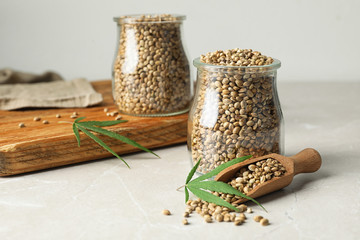Organic hemp seeds and leaves on light marble table