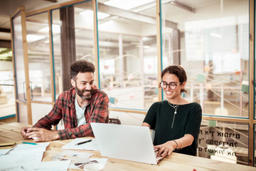 Smiling carpenters working over laptop at desk in office