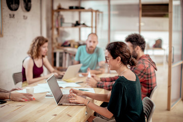 Smiling female carpenter using laptop with colleagues working at desk in office