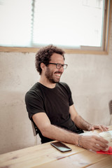 Cheerful male carpenter looking away while sitting at desk in office