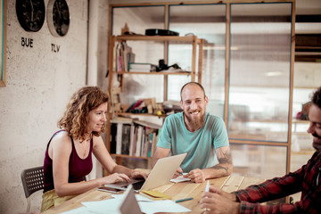 Smiling carpenter looking at colleague while sitting in office