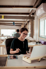 Smiling female carpenter using laptop at desk in office