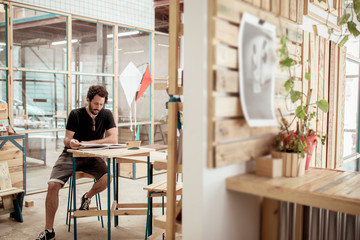 Full length of male carpenter reading magazine at desk in workshop