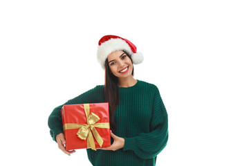 Happy young woman in Santa hat with Christmas gift on white background