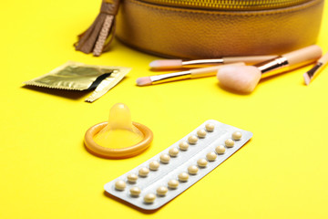 Condom and birth control pills on yellow background. Safe sex concept