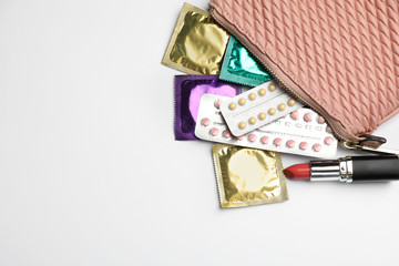 Flat lay composition with birth control pills and condoms on light background, space for text. Safe...