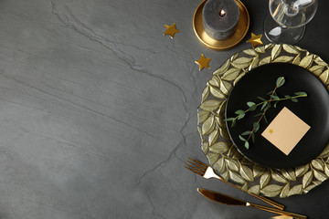 Elegant festive table setting with blank card on dark grey background, flat lay. Space for text