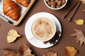 Flat lay composition with cup of hot drink on brown background. Cozy autumn atmosphere