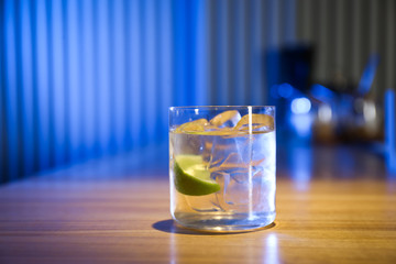 Glass of delicious cocktail with vodka on wooden counter in bar