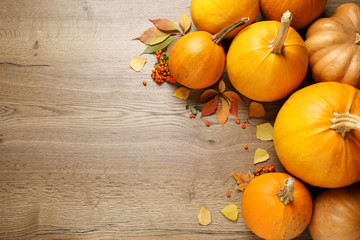 Flat lay composition with different ripe pumpkins on wooden background, space for text. Holiday decoration