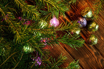 Obraz na płótnie Canvas Christmas tree branches, candies in multi-colored shiny wrappers and LED lights lie on a natural wooden surface made of pine boards. Night magic