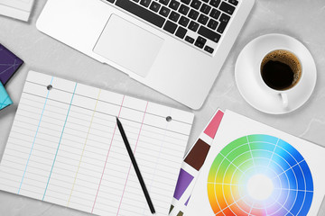 Flat lay composition with notebook, laptop and color palettes on light grey marble table....