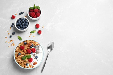 Healthy homemade granola with yogurt and berries served on light grey table, flat lay. Space for text