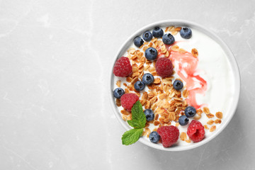 Healthy homemade granola with yogurt and berries on light grey table, top view. Space for text