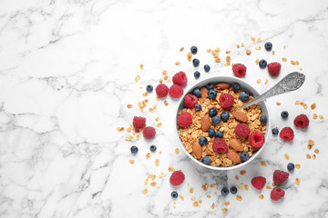 Healthy homemade granola with berries and almonds on white marble table, top view. Space for text