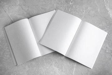 Blank open books on light grey marble background, top view. Mock up for design