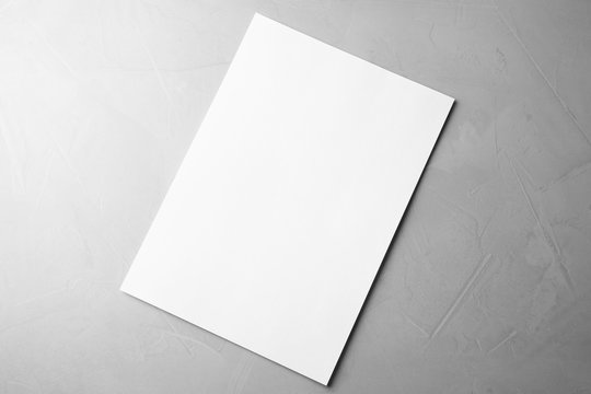 Blank paper sheet on light grey stone background, top view. Mock up for design
