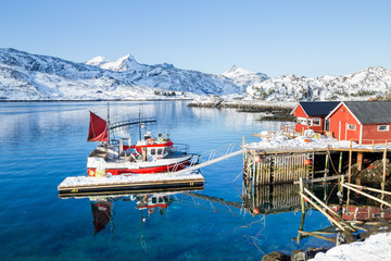 Red fisherman´s house on Lofoten islands in front of a fjord at a beautiful sunny winter day