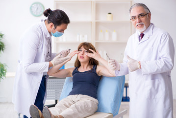 Obraz premium Two male doctors and young woman in plastic surgery concept