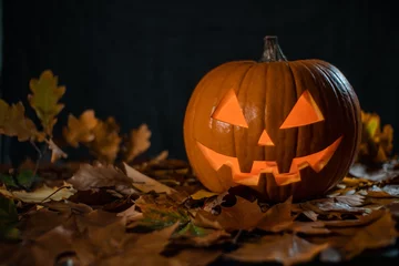Foto op Plexiglas halloween carving pumpkin on a leafs. shining Jack-o'-lantern. © sashkasiro