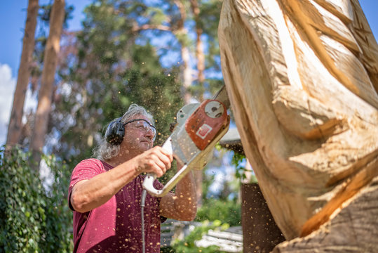 Wood carver carving sculpture, using chainsaw