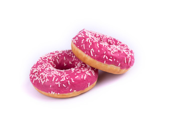 two donuts are shown close. One lies on top of the other at the edge, covered with pink icing and decorated with white powde