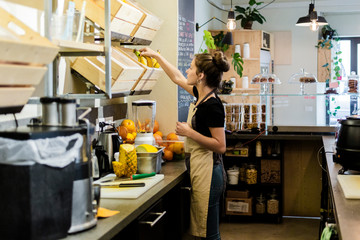 Young woman working in a cafe preparing a fresh drink
