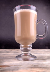 Front view of a cup of aromatic coffee standing on wooden textured background