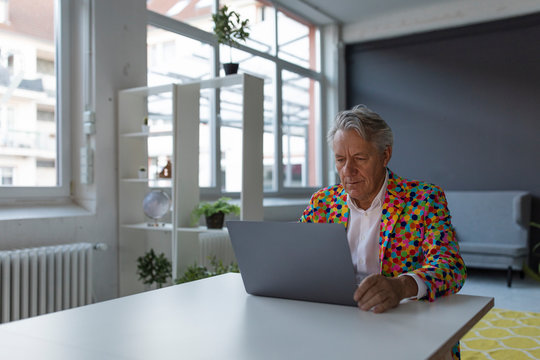 Senior businessman wearing colorful sports jacket using laptop