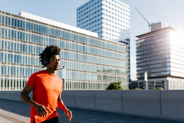Young man jogging in the city, listening to music