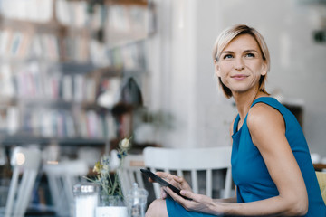 Businesswoman sitting in coffee shop, using digital tablet
