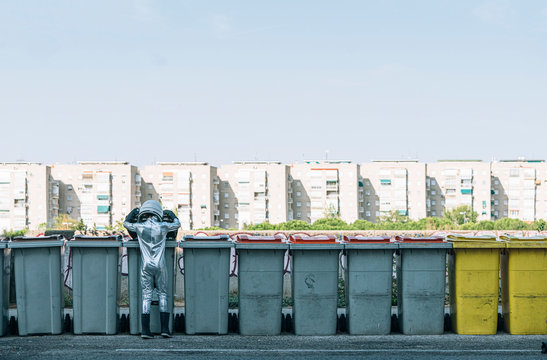 Rear view of boy dressed as an astronaut at garbage cans in the city