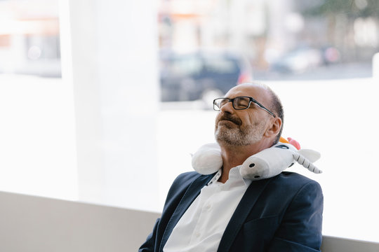 Businessman taking a nap, with a unicorn pillow around his neck