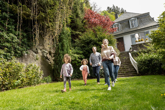 Happy extended family walking in garden of their home