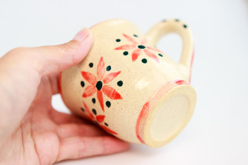 beige clay cup with flowers in hand on a white background