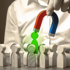 A hand with a magnet pulls green human figure out of the big crowd of people. demand for...