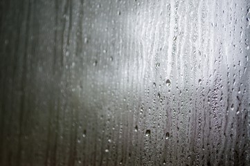 The fog on the window glass, , partially blurred. Drops of rain