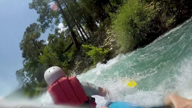 Rafting on a mountain river. Young people kayaking on a mountain river and a lot of splashing on their faces. 
